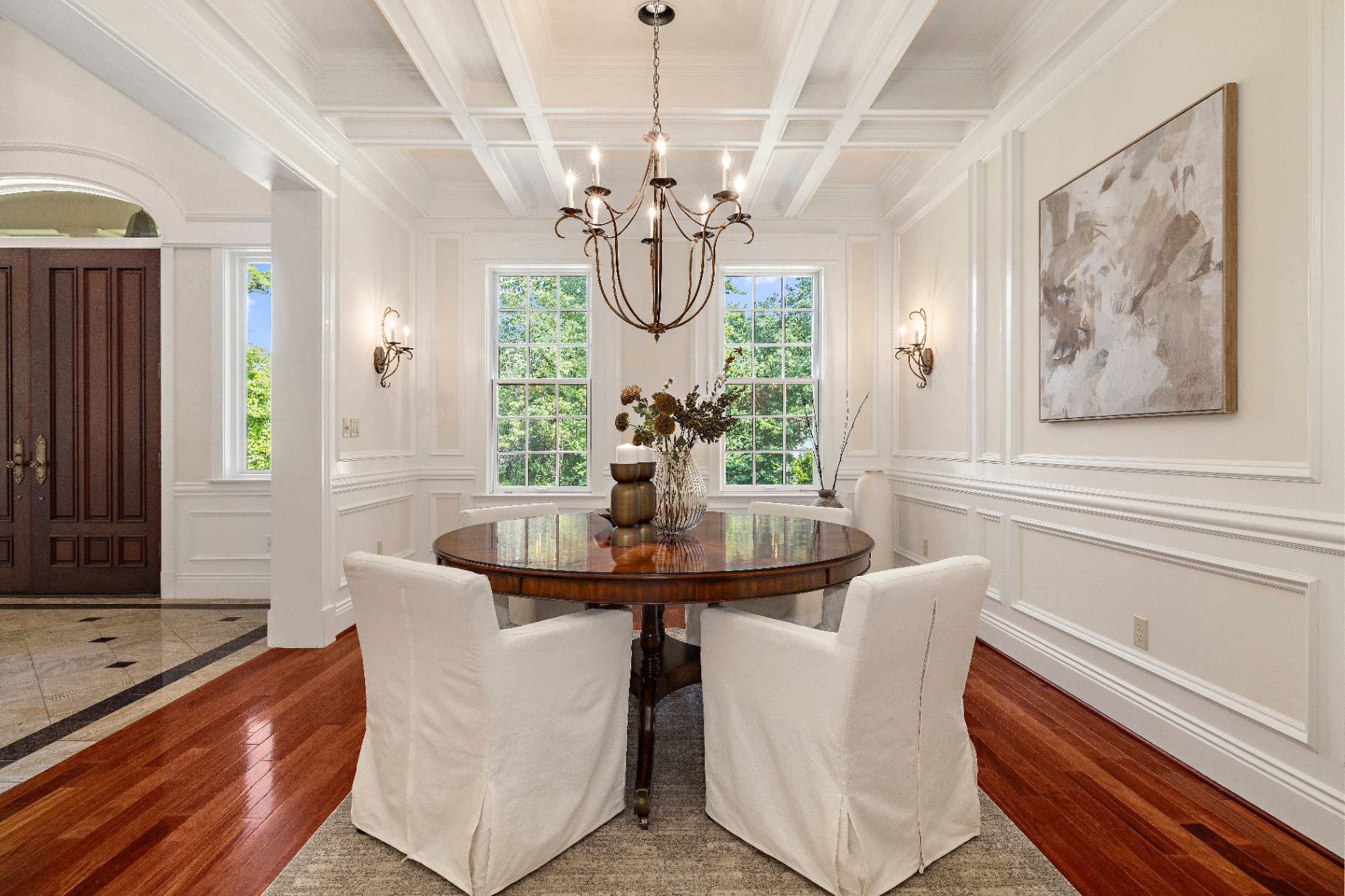 Formal dining room with coffered ceiling, chandelier, and view through to the front doors