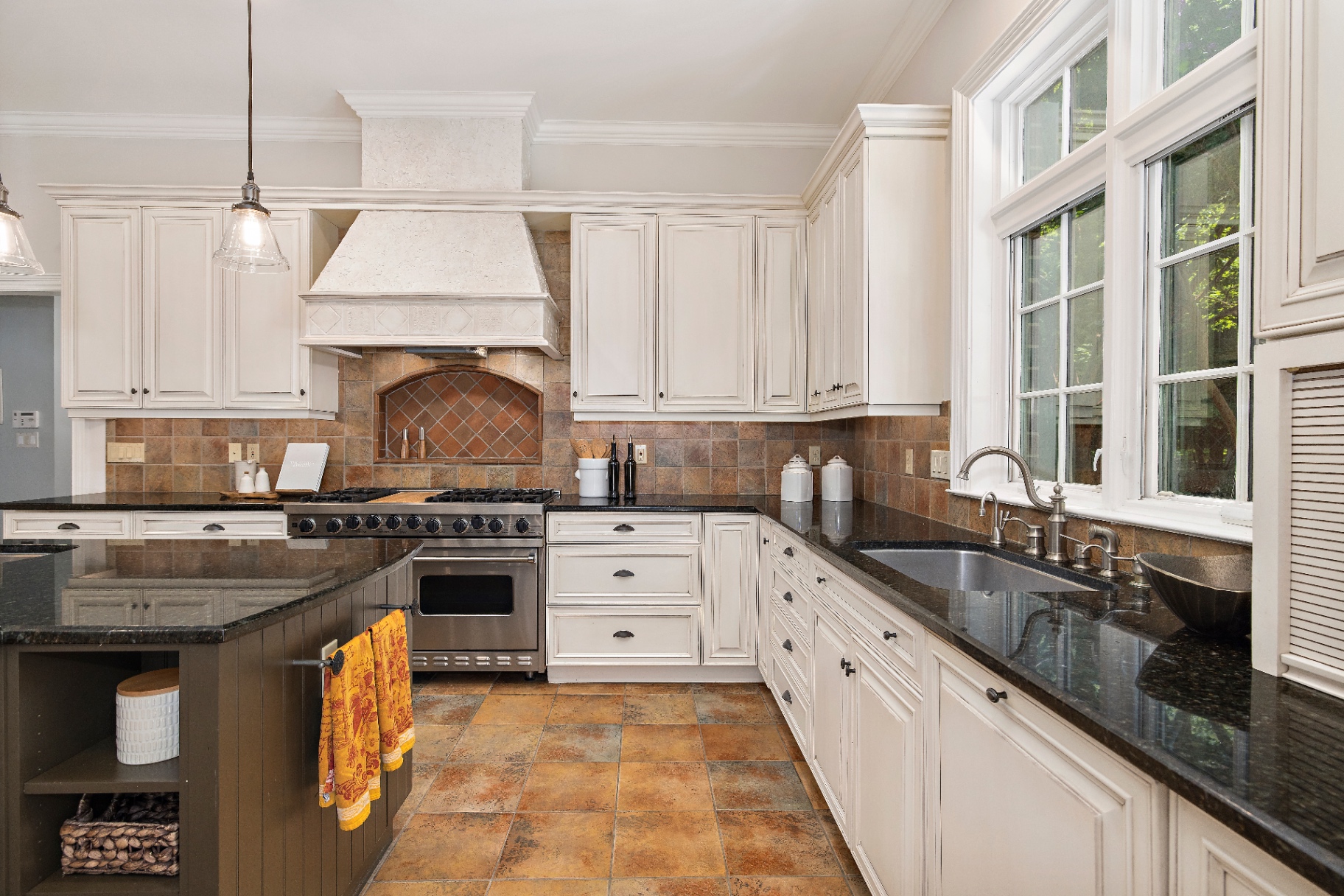 Chef's kitchen with custom hood, professional gas range, granite counters, and slate tile floor