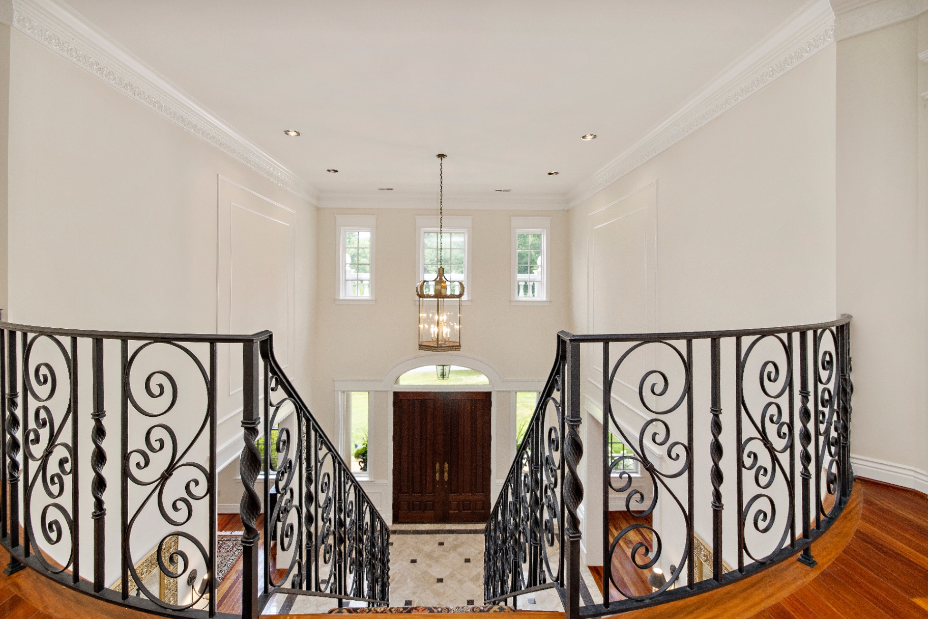 Grand two-story foyer looking up the staircase to the second-floor gallery and heirloom painting