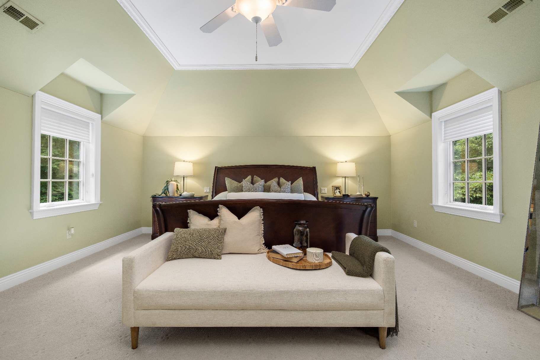 Primary bedroom with sleigh bed, vaulted ceiling, and dual windows overlooking the trees