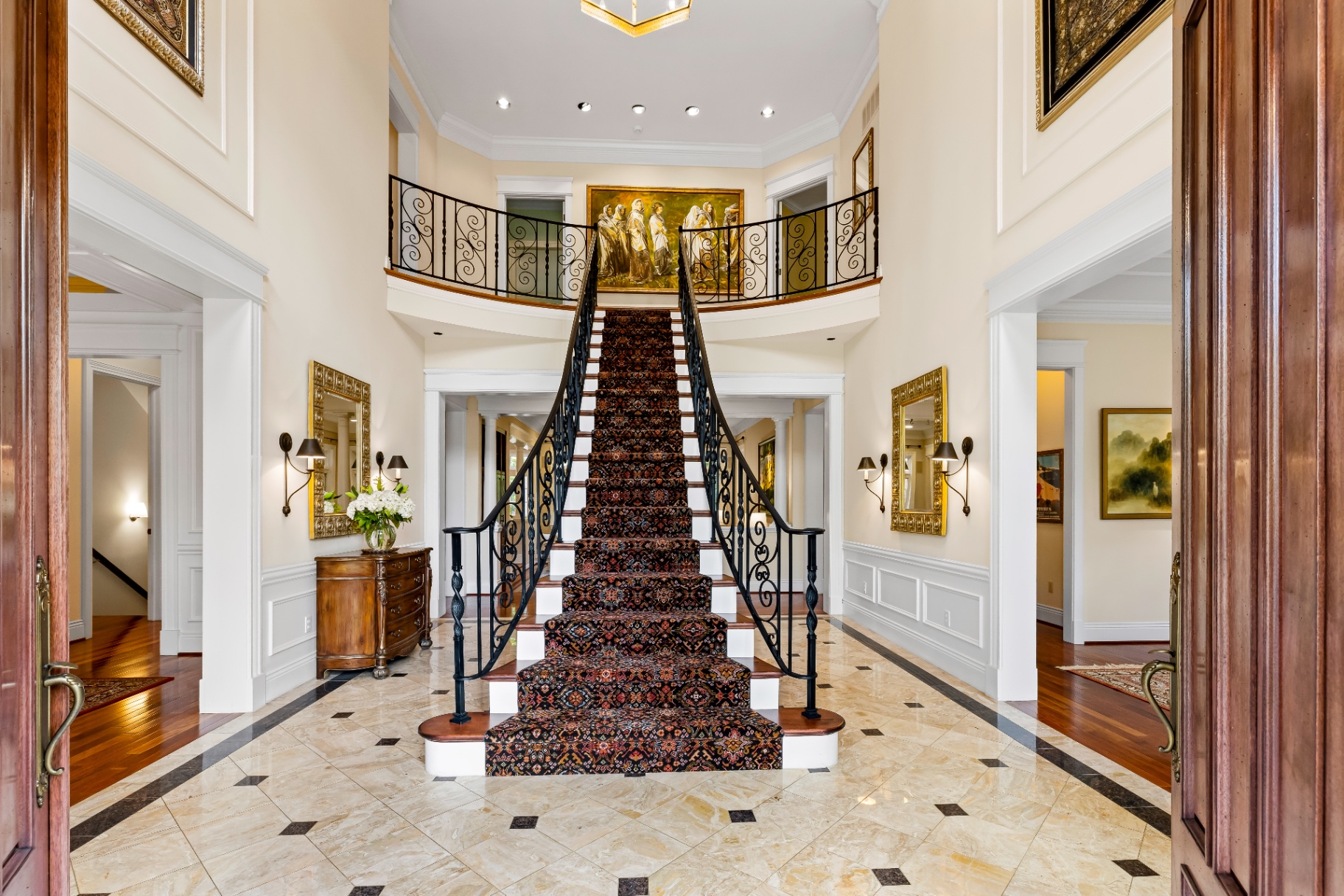 Grand foyer with sweeping staircase, Persian runner, and gilded mirrors