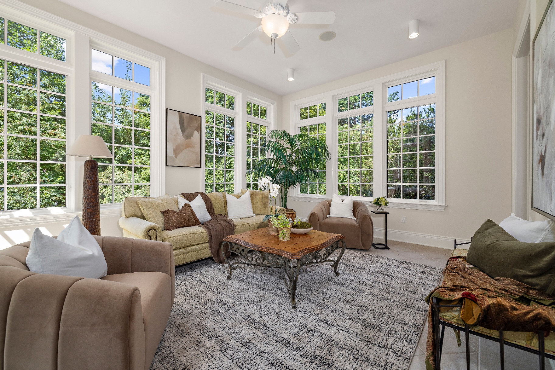 Sunroom with wall of windows overlooking the trees, comfortable seating, and hand-carved coffee table