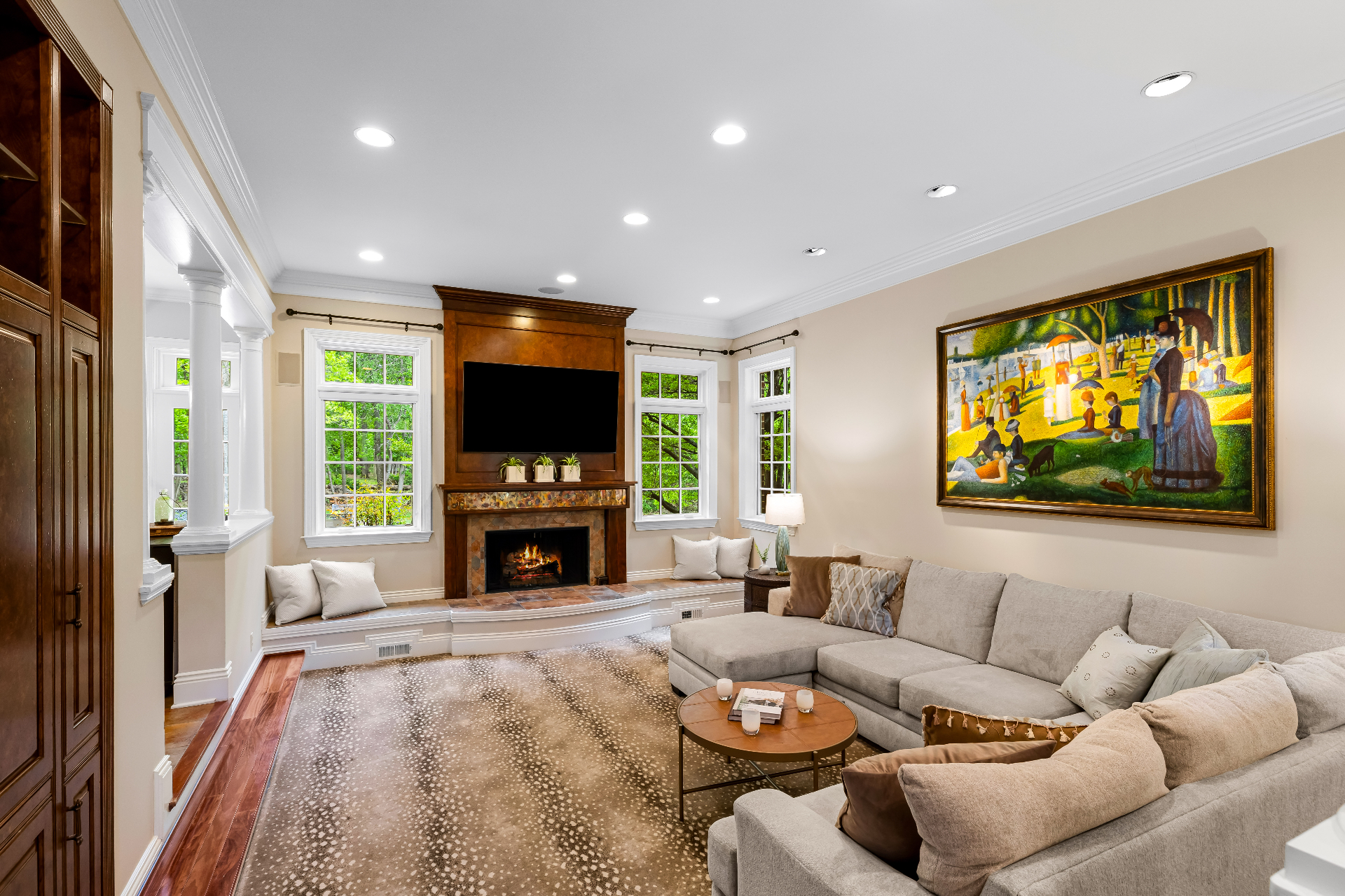 Family room with sectional sofa, fireplace, mounted TV, and large windows to the trees