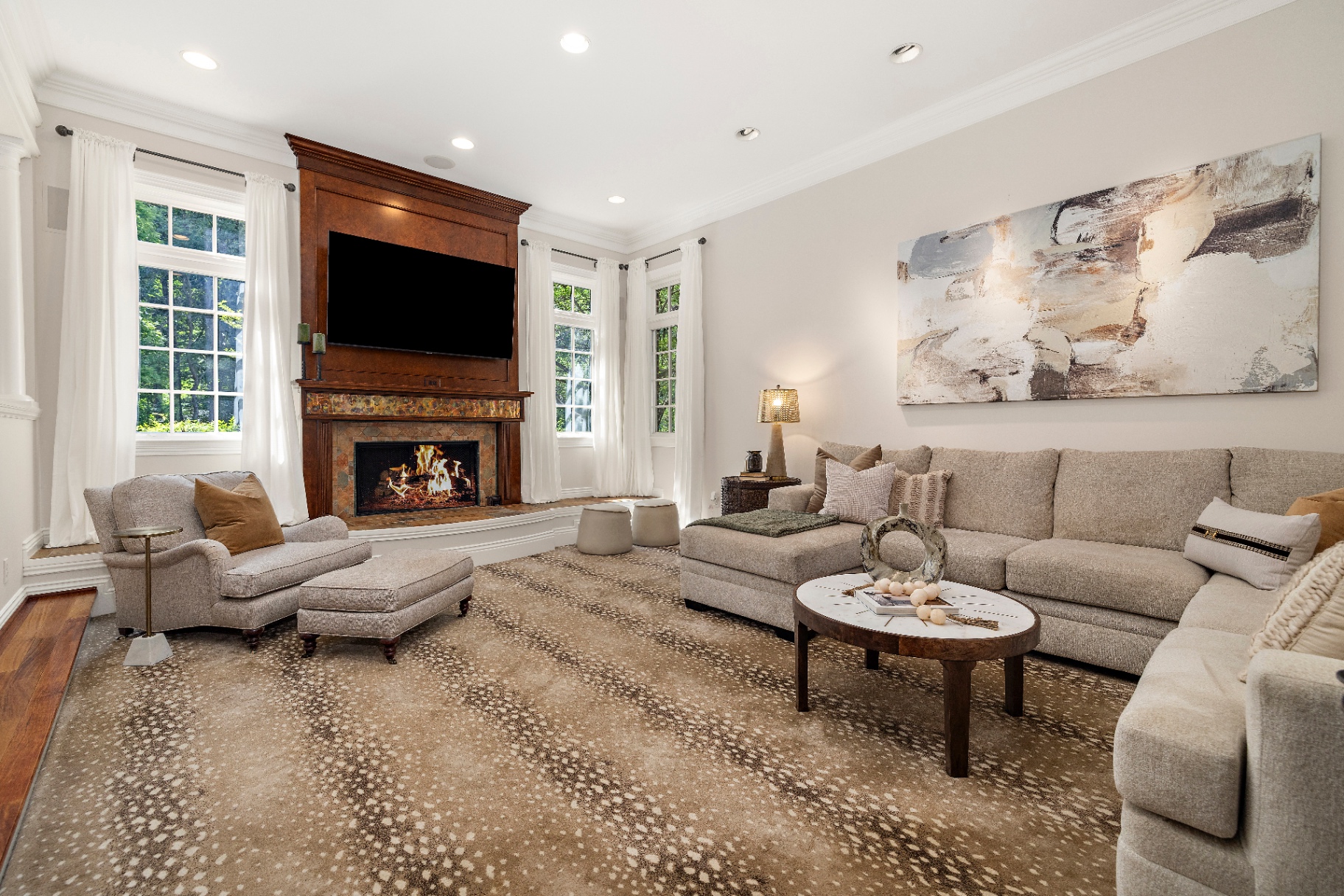 Family room with sectional sofa, fireplace, mounted TV, and large windows to the trees